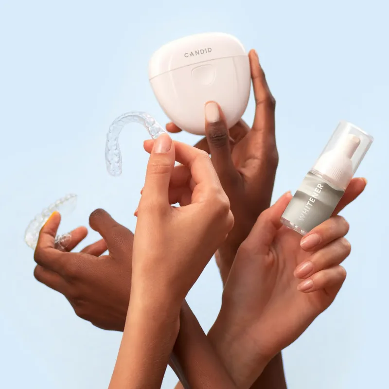 Hands holding clear aligner products against a light blue background